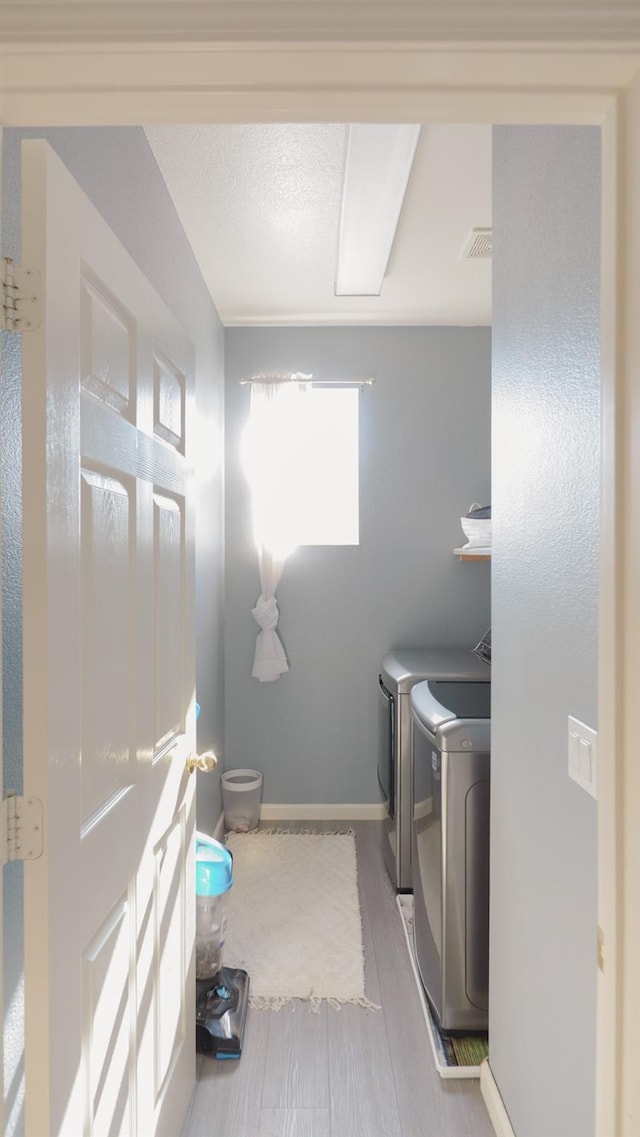 laundry room with a healthy amount of sunlight, washer and dryer, visible vents, and wood finished floors