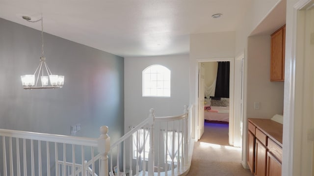 hallway with visible vents, light colored carpet, an upstairs landing, and a notable chandelier