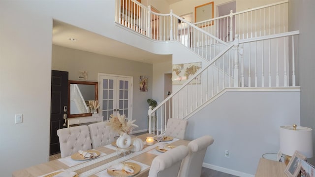 dining room featuring french doors, a high ceiling, baseboards, and stairs