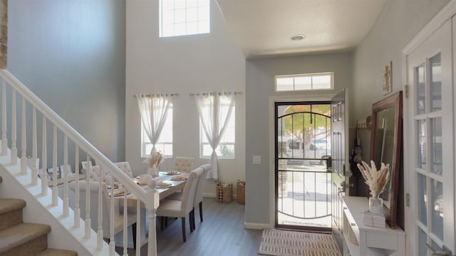 entryway featuring baseboards, wood finished floors, a towering ceiling, and stairs