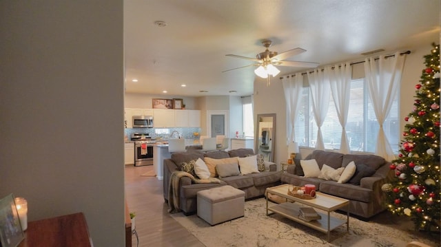 living area featuring light wood-style floors, a ceiling fan, and recessed lighting