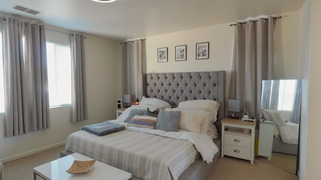 bedroom featuring light carpet, visible vents, multiple windows, and baseboards