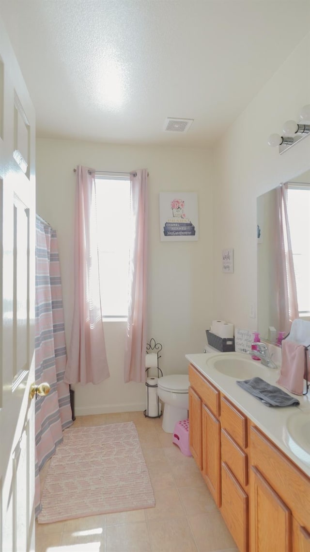 bathroom featuring tile patterned floors, plenty of natural light, visible vents, and toilet