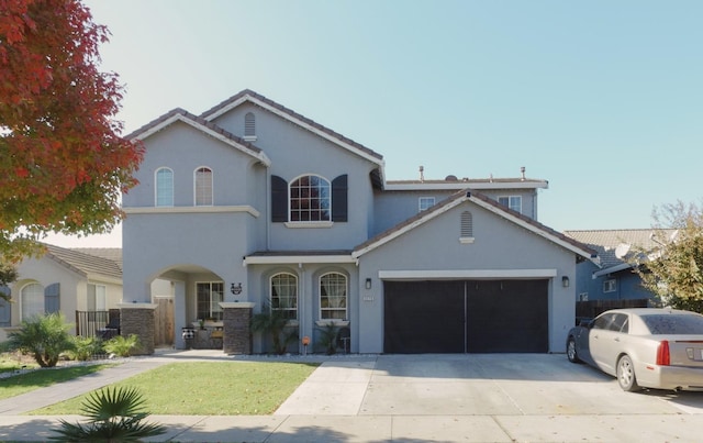 mediterranean / spanish house with concrete driveway, a tile roof, a garage, and stucco siding
