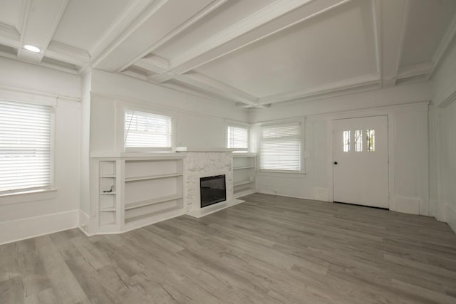unfurnished living room featuring coffered ceiling, beam ceiling, a premium fireplace, and wood finished floors
