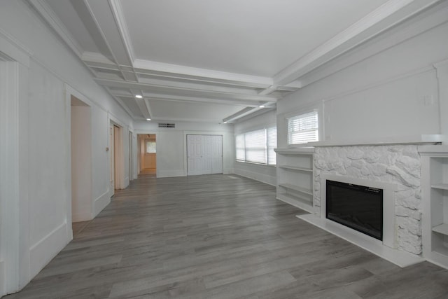unfurnished living room featuring baseboards, a stone fireplace, beam ceiling, and wood finished floors