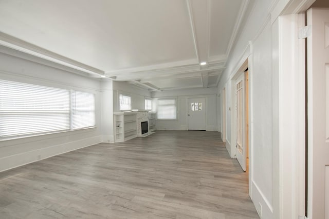 unfurnished living room featuring beam ceiling, ornamental molding, light wood-type flooring, a fireplace, and baseboards
