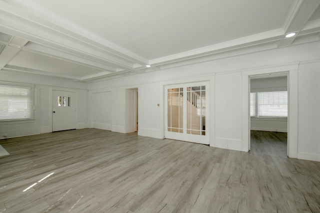 unfurnished living room with beam ceiling, baseboards, and light wood-style floors