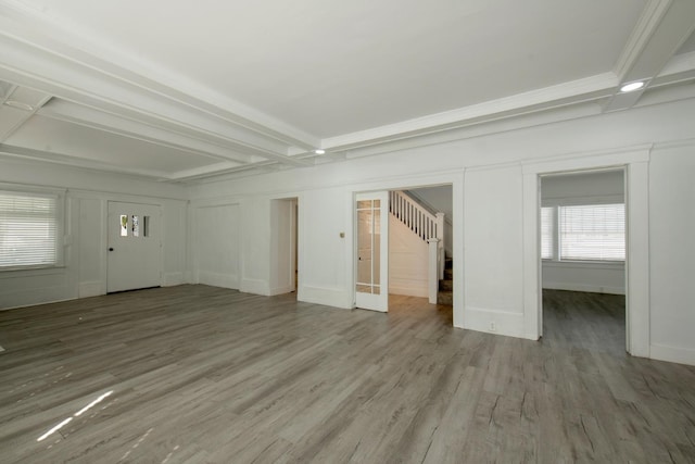 unfurnished living room featuring stairway, beam ceiling, and wood finished floors