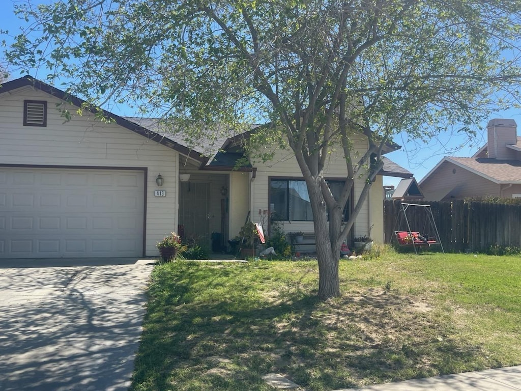 ranch-style house featuring concrete driveway, a front lawn, fence, and an attached garage
