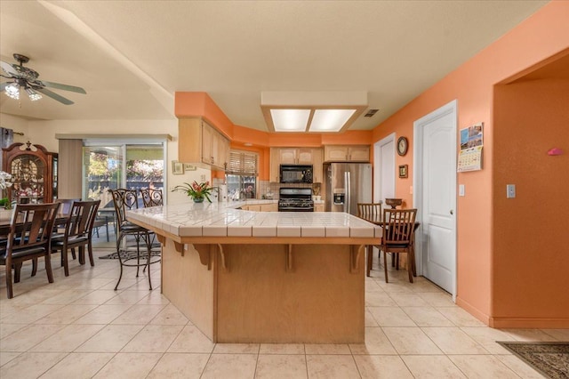 6305 N Marty Ave, Fresno, CA 93711 - kitchen featuring light tile patterned floors, black appliances, tile countertops, and a peninsula