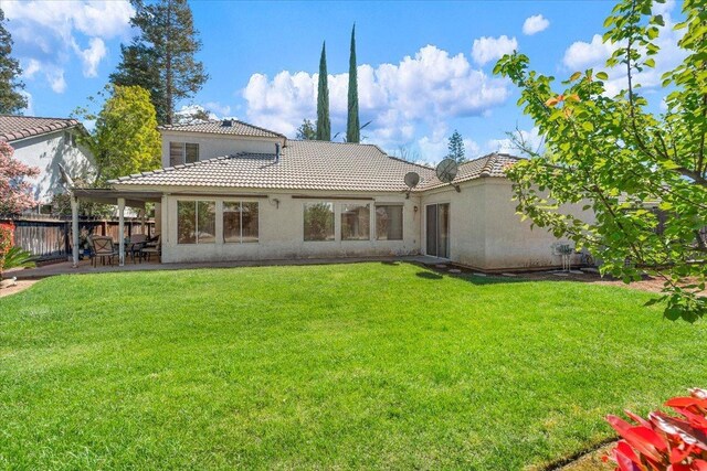 6305 N Marty Ave, Fresno, CA 93711 - back of house featuring a patio area, a lawn, a tile roof, fence, and stucco siding