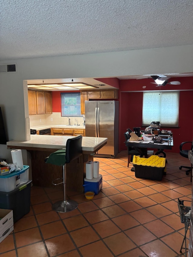 1225 Pontiac Ave, Clovis, CA 93612 - kitchen featuring freestanding refrigerator, light tile patterned floors, a peninsula, and a textured ceiling