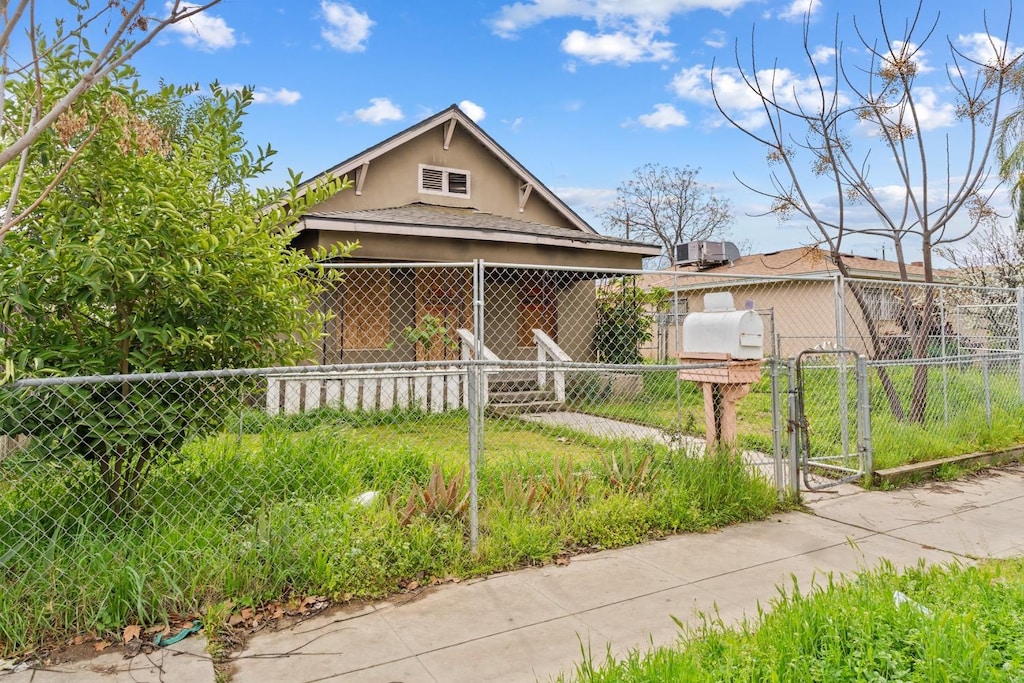 bungalow-style home featuring stucco siding, fence, and a gate