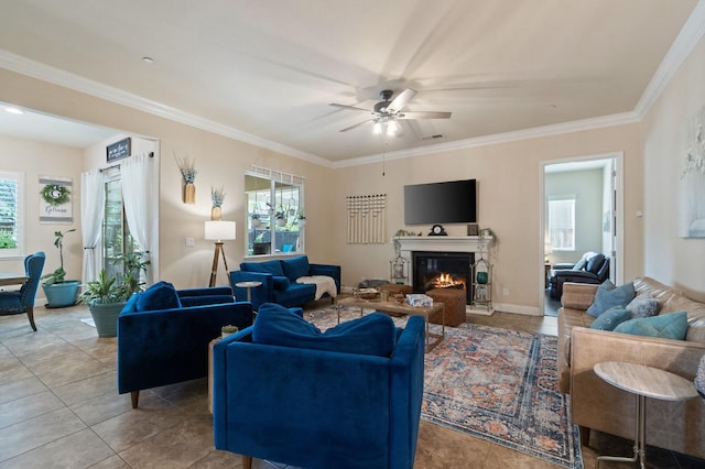 tiled living area featuring ornamental molding, ceiling fan, a wealth of natural light, and a glass covered fireplace