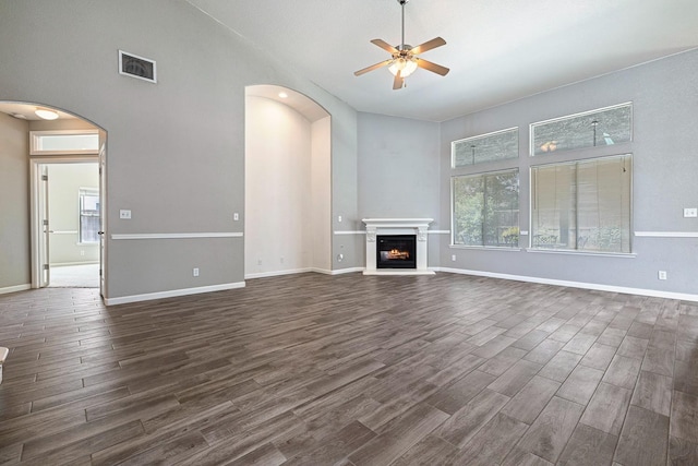 4650 W Roberts Ave, Fresno, CA 93722 - unfurnished living room with arched walkways, dark wood-style flooring, a ceiling fan, healthy amount of natural light, and a high ceiling