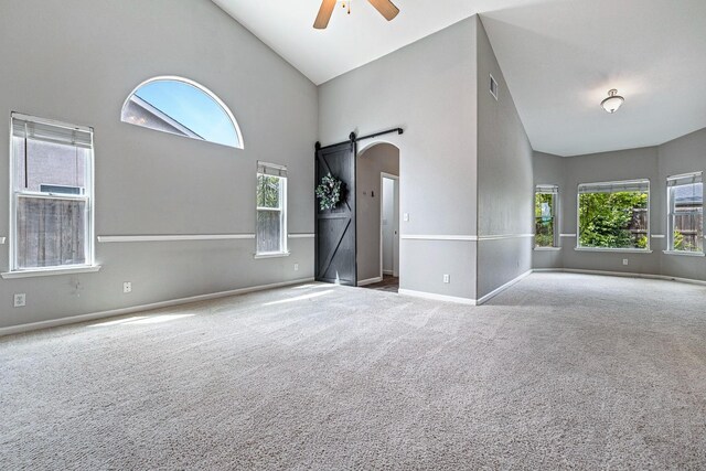 4650 W Roberts Ave, Fresno, CA 93722 - carpeted empty room with a barn door, ceiling fan, plenty of natural light, and high vaulted ceiling