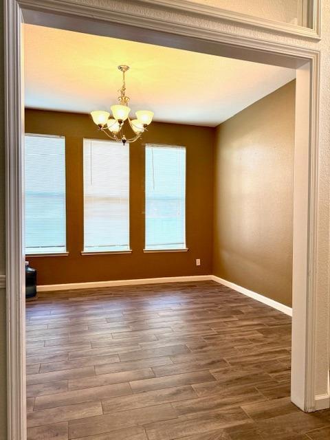 4650 W Roberts Ave, Fresno, CA 93722 - unfurnished dining area featuring a chandelier, baseboards, and wood finished floors