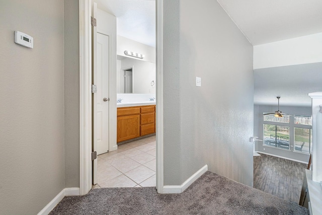 4650 W Roberts Ave, Fresno, CA 93722 - hallway with light colored carpet, baseboards, and light tile patterned floors