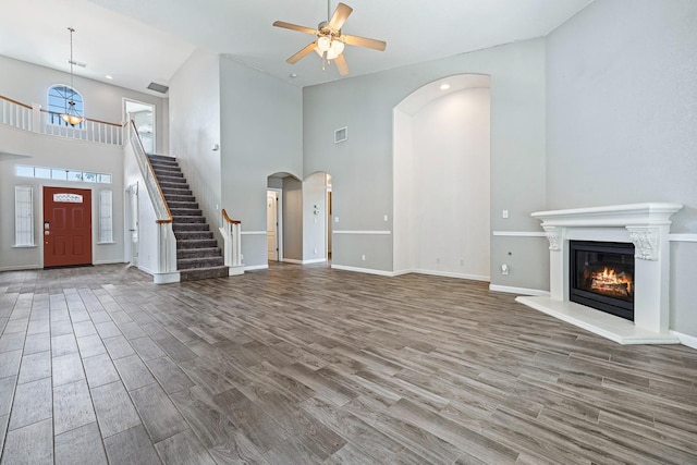 4650 W Roberts Ave, Fresno, CA 93722 - unfurnished living room featuring high vaulted ceiling, ceiling fan, wood finished floors, a glass covered fireplace, and arched walkways