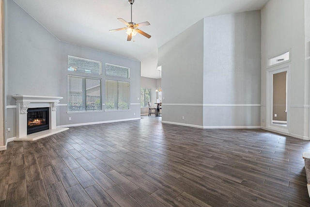 4650 W Roberts Ave, Fresno, CA 93722 - unfurnished living room with high vaulted ceiling, ceiling fan, a glass covered fireplace, dark wood finished floors, and baseboards