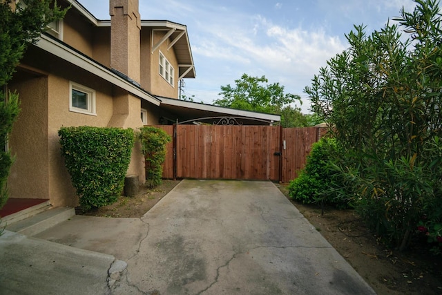 view of home's exterior with fence, stucco siding, a gate, and a chimney