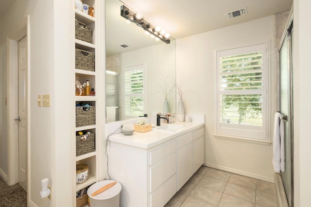 bathroom featuring visible vents, a shower with shower door, tile patterned floors, baseboards, and vanity