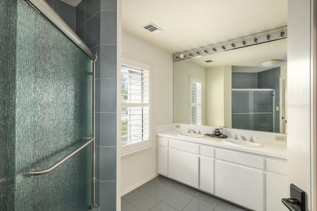 full bath with visible vents, a sink, tile patterned flooring, and a stall shower