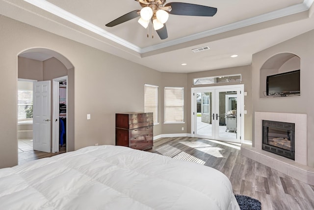 bedroom with visible vents, arched walkways, crown molding, wood finished floors, and access to exterior