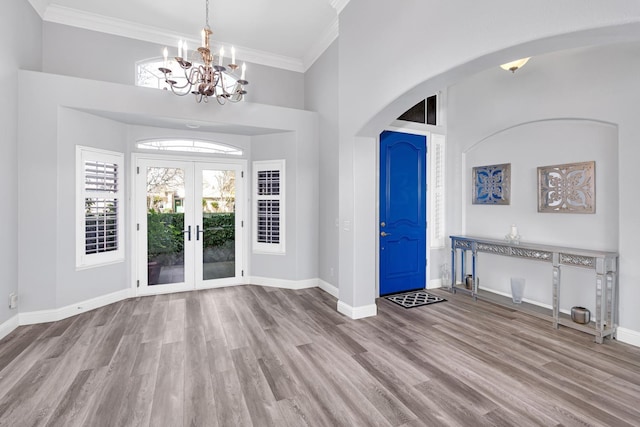 foyer entrance featuring arched walkways, wood finished floors, a notable chandelier, and baseboards