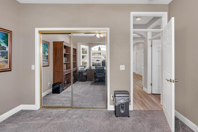 bedroom with carpet floors, baseboards, arched walkways, and a closet