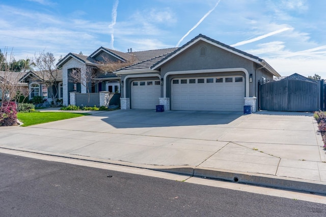 ranch-style house with an attached garage, stone siding, concrete driveway, stucco siding, and a gate