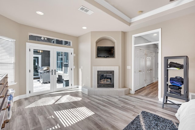 living area featuring crown molding, french doors, a wealth of natural light, and visible vents