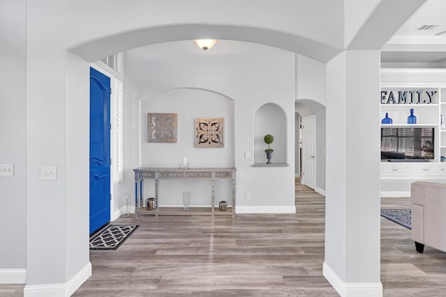 interior space with arched walkways, wood finished floors, baseboards, and visible vents