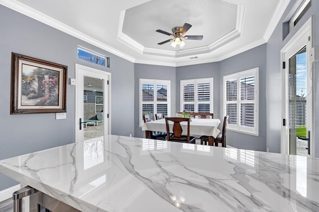 dining space featuring visible vents, a tray ceiling, ornamental molding, and ceiling fan