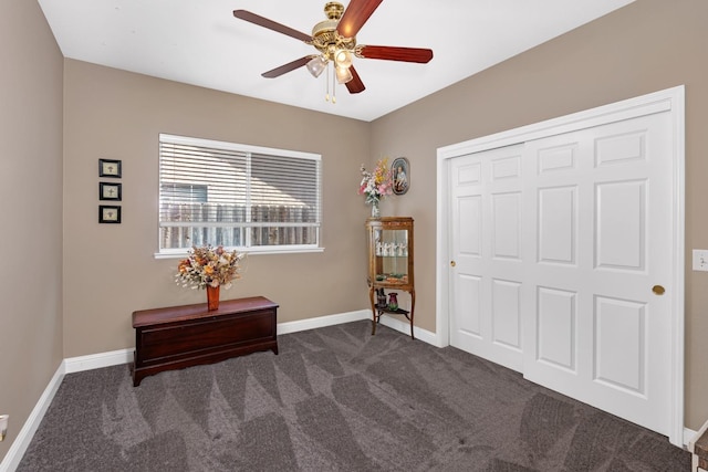 interior space with dark carpet, a closet, ceiling fan, and baseboards