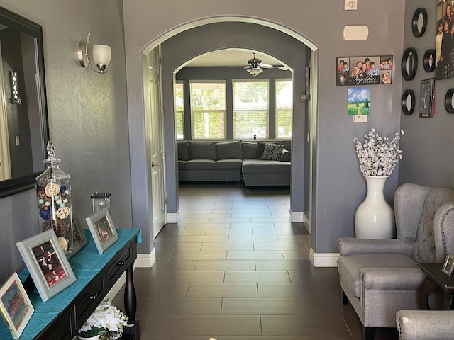 hall featuring baseboards and arched walkways