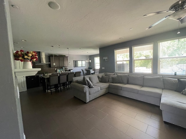 living room featuring a textured ceiling, dark tile patterned floors, and a ceiling fan