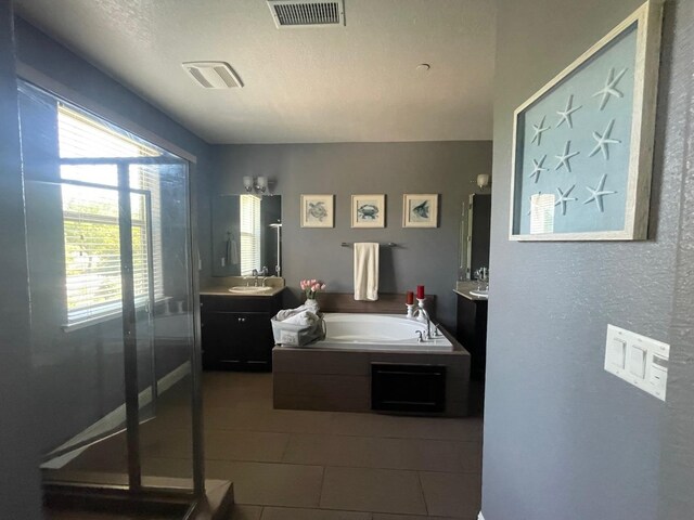 bathroom featuring tile patterned floors, vanity, visible vents, and a bath