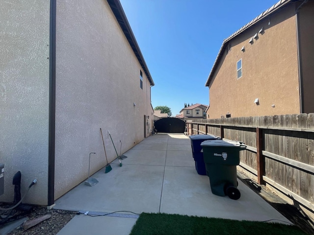 view of side of property with a patio area, stucco siding, and fence