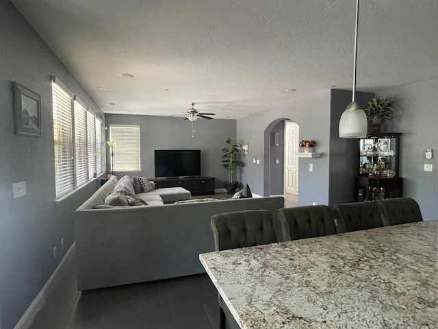 living area featuring arched walkways, ceiling fan, and baseboards