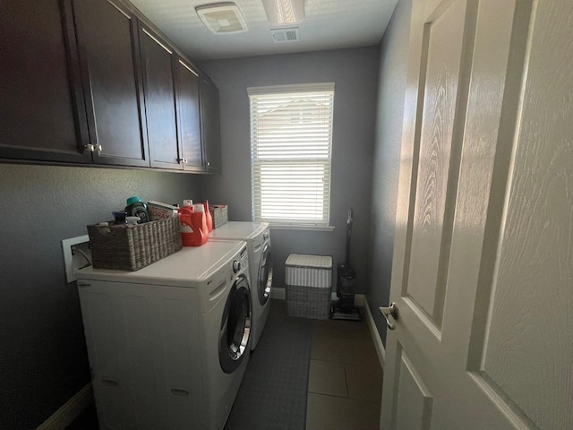 laundry area featuring visible vents, baseboards, dark tile patterned floors, cabinet space, and washer and clothes dryer