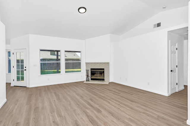 5873 W Wathen, Fresno, CA 93722 - unfurnished living room featuring light wood-style floors, lofted ceiling, baseboards, and a brick fireplace