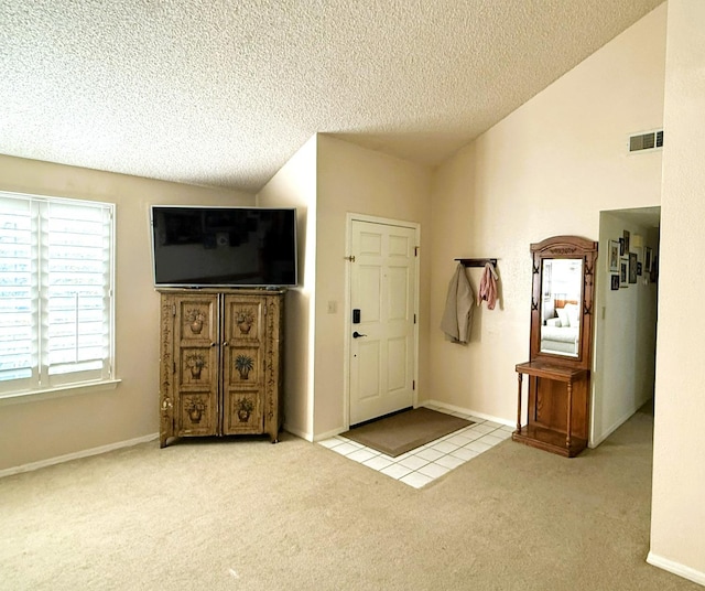 entryway with lofted ceiling, carpet flooring, a textured ceiling, and tile patterned floors