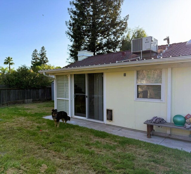 back of house with central AC and a chimney