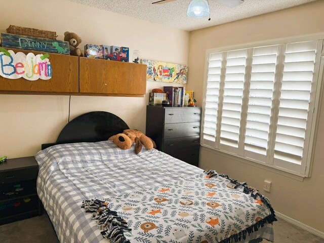 carpeted bedroom featuring baseboards, a textured ceiling, and ceiling fan