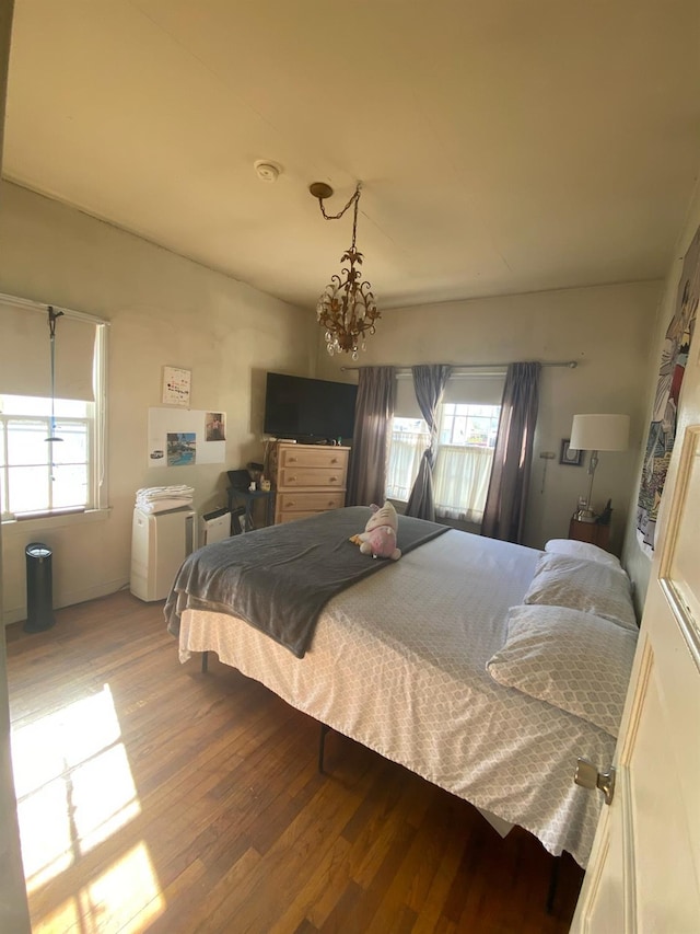 bedroom featuring multiple windows, a notable chandelier, and wood finished floors