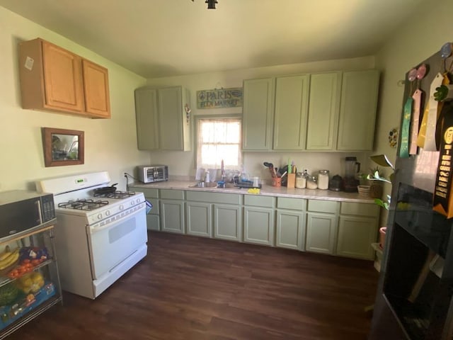 kitchen with white gas stove, light countertops, dark wood-style flooring, and a sink