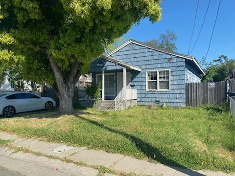 bungalow-style home with fence and a front lawn