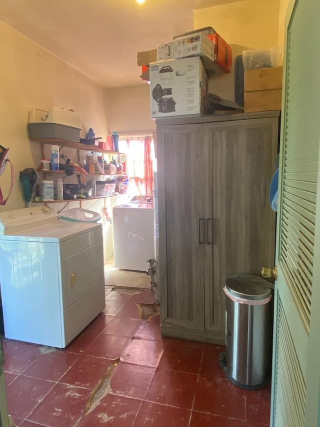 washroom with dark tile patterned flooring, laundry area, and washing machine and dryer